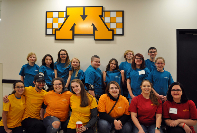 Students gathered in front of the University of Minnesota logo